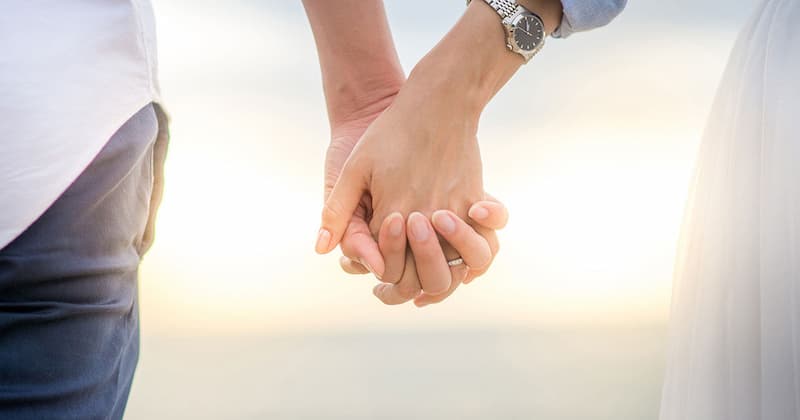 Couple holding hands in the sunshine after reconnecting through couples therapy
